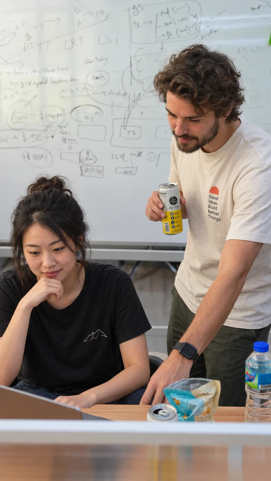 Two collaborators planning their work together beside a whiteboard