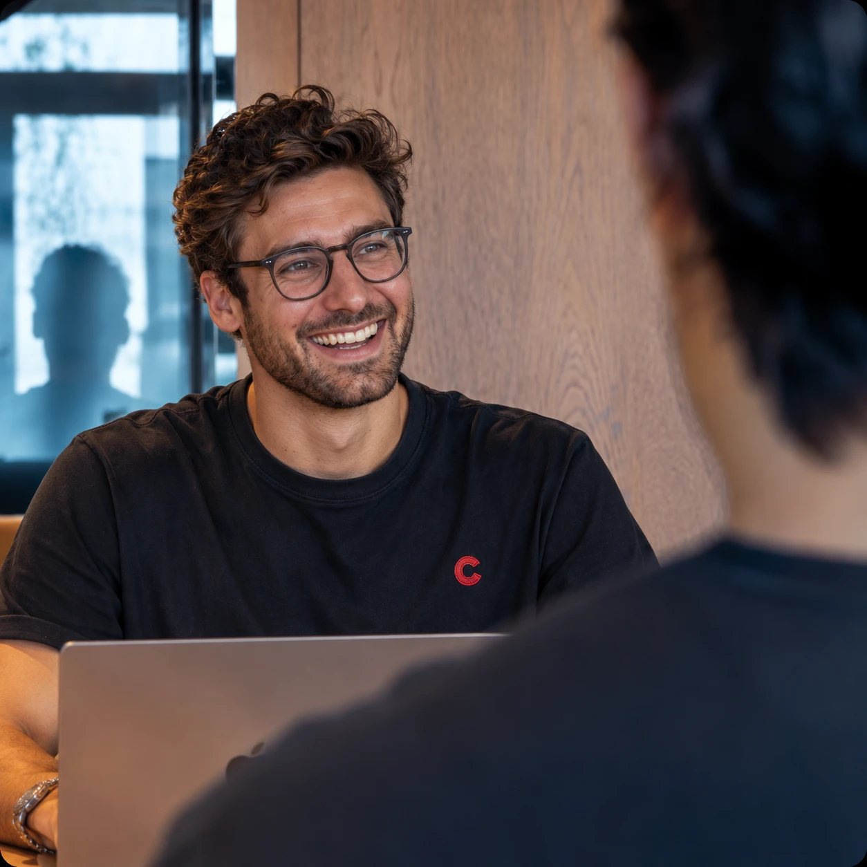 A smiling creator working on his laptop with a collaborator