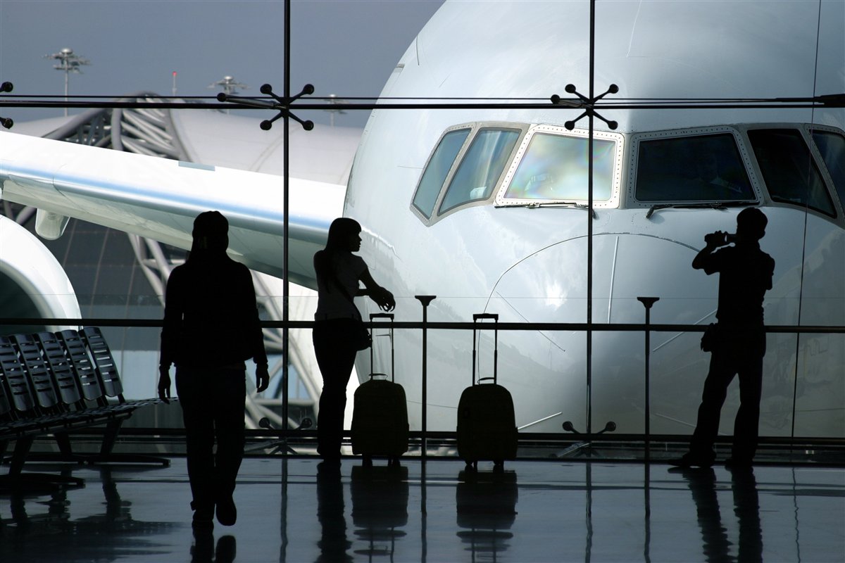 Travellers waiting beside an aircraft at an international airport